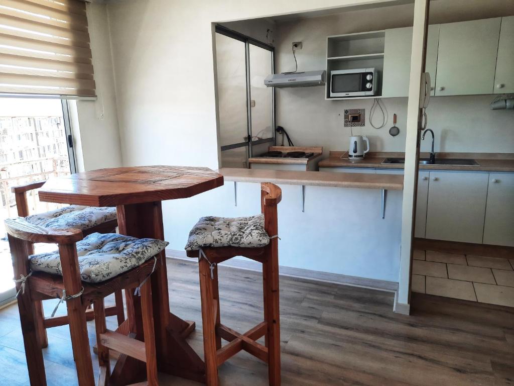 une cuisine avec une table en bois et deux tabourets dans l'établissement Departamento Centro de Temuco, à Temuco