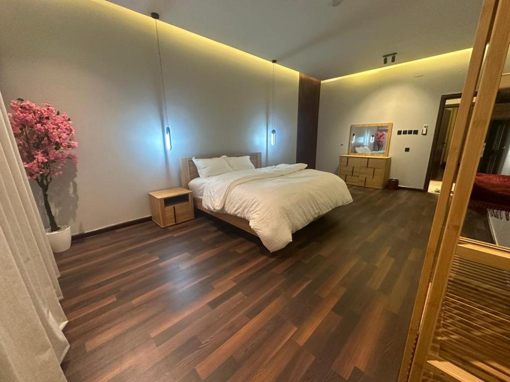 a bedroom with a large bed and wooden floors at تربل فور سويت - شقة في فيلا in Al Başar