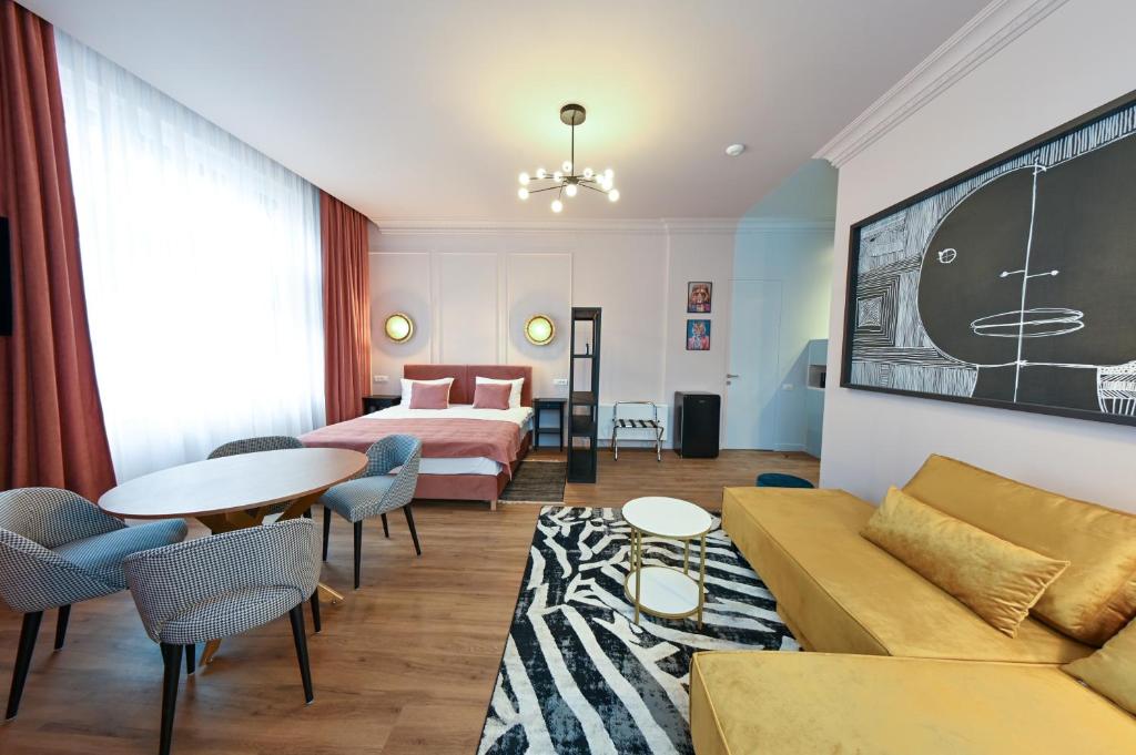 um quarto de hotel com uma cama, um sofá e uma mesa em Leda Residence em Oradea