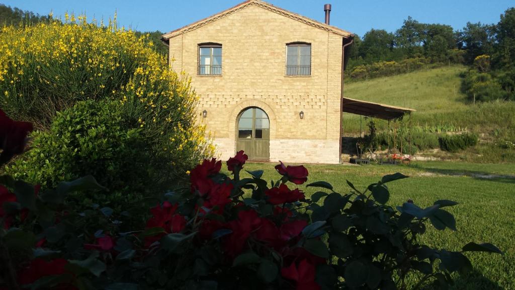 a house on a hill with flowers in front of it at Agriturismo Serracanina in Cagli