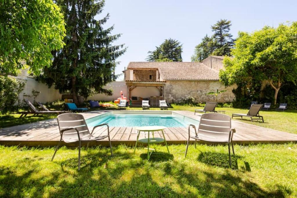 a backyard with a pool with chairs and a table at Chateau La Fontaine in Fronsac