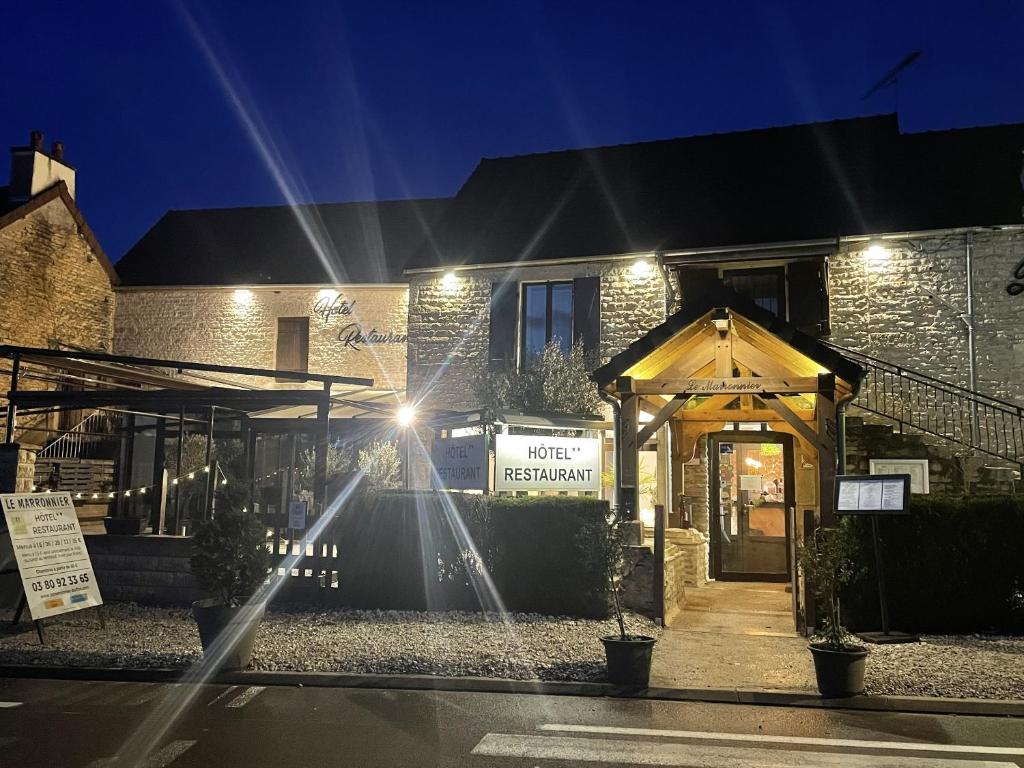 a building with a sign on the front of it at night at Logis Le Marronnier in Buffon