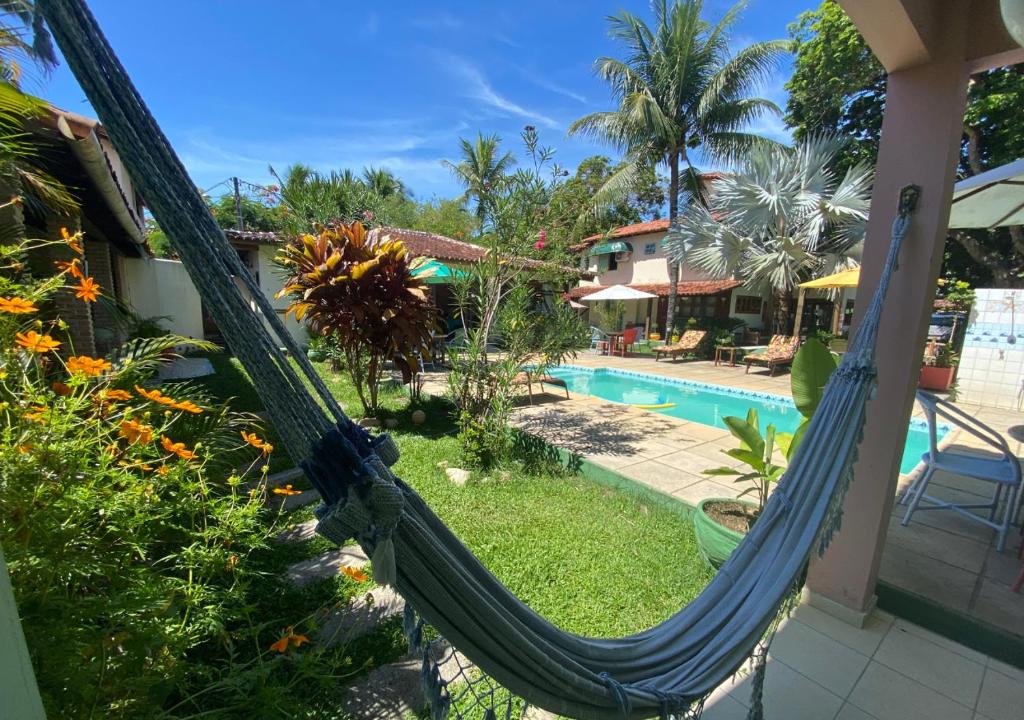 a hammock in front of a house with a swimming pool at Pousada Cantinho do Sossego in Arraial d'Ajuda