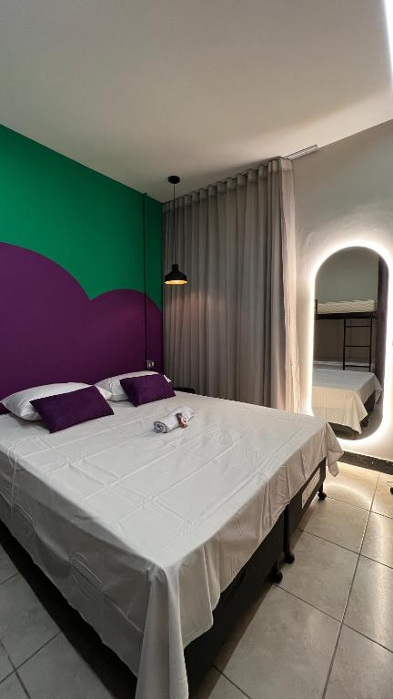 a bedroom with a large bed with a green and purple wall at Belô Hostel in Belo Horizonte