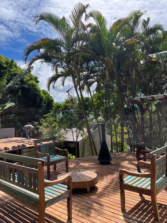 three wooden benches sitting on a wooden deck with palm trees at Pousada Maikai Garden in Porto Belo