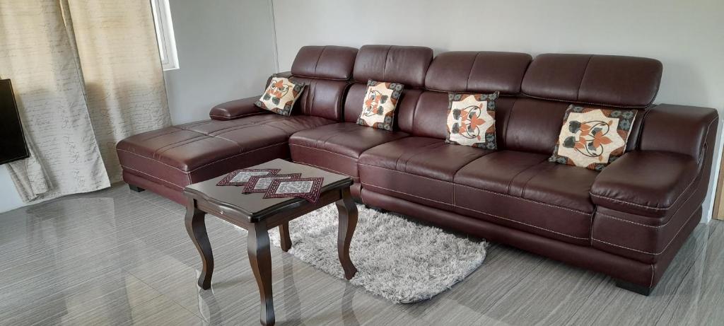 um sofá de couro castanho numa sala de estar com uma mesa em Cozy Appartment em Trianon