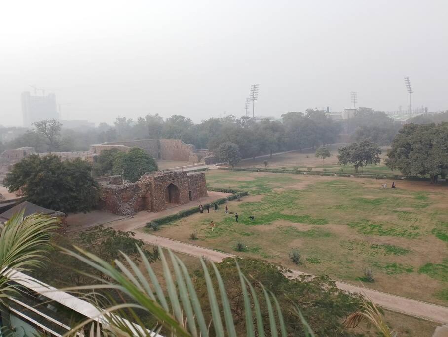 Blick auf einen Park mit einem Gebäude und einem Feld in der Unterkunft Homlee-Vintage Green 2BHK with Terrace & fort View in Neu-Delhi