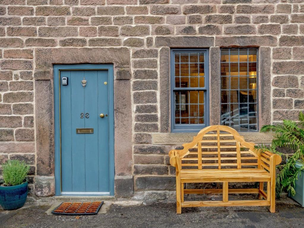 eine blaue Tür und eine Holzbank vor einem Gebäude in der Unterkunft 3 bed in Cromford 78591 in Cromford