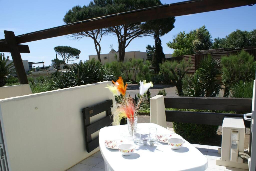 une table blanche avec un vase de fleurs sur un balcon dans l'établissement Studio 411, Port Nature 4 au village naturiste, au Cap d'Agde