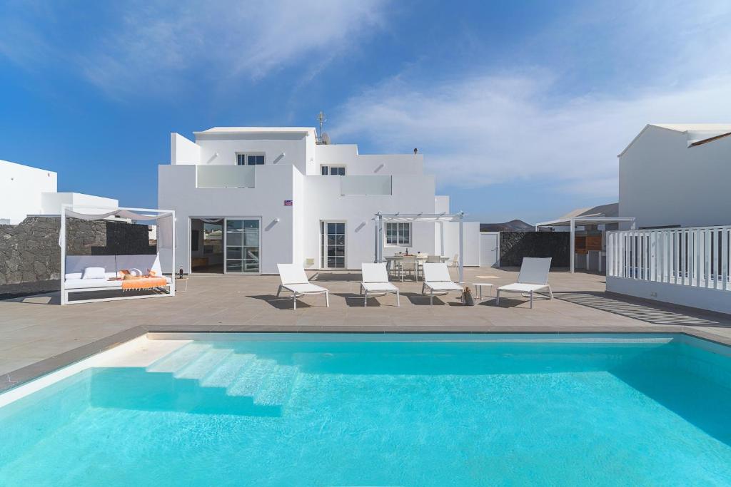 einen Pool vor einem weißen Haus in der Unterkunft VV Villa Secretos de Yaiza 3 by HH - private pool & BBQ in Yaiza