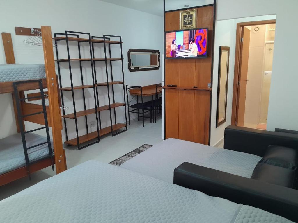 una camera con letto, TV e letti a castello di Condomínio da Fé - Studio Loft - 12º andar a Cachoeira Paulista