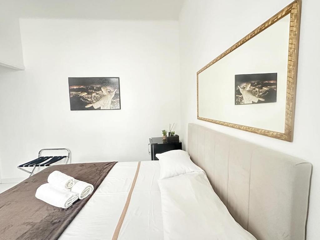 - une chambre blanche avec un lit en bois et un miroir mural dans l'établissement Studio'S Bartho Leblon, à Rio de Janeiro