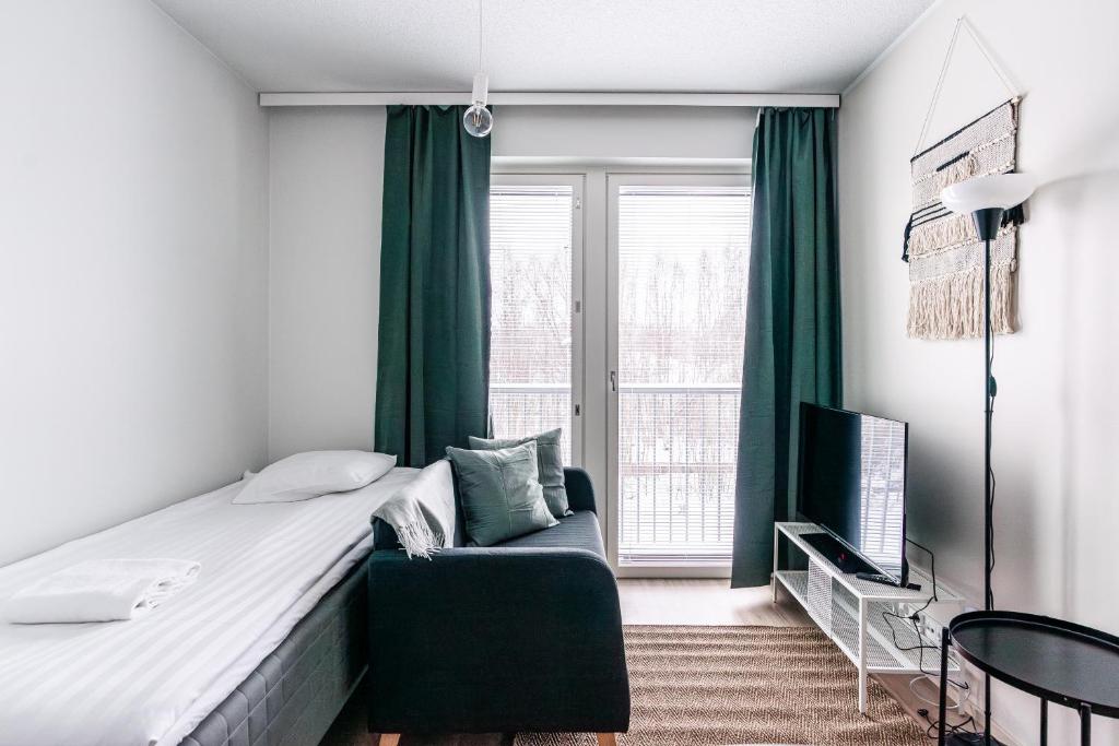 a bedroom with a bed and a chair and a window at SPOT Apartments Hämeenlinna in Hämeenlinna
