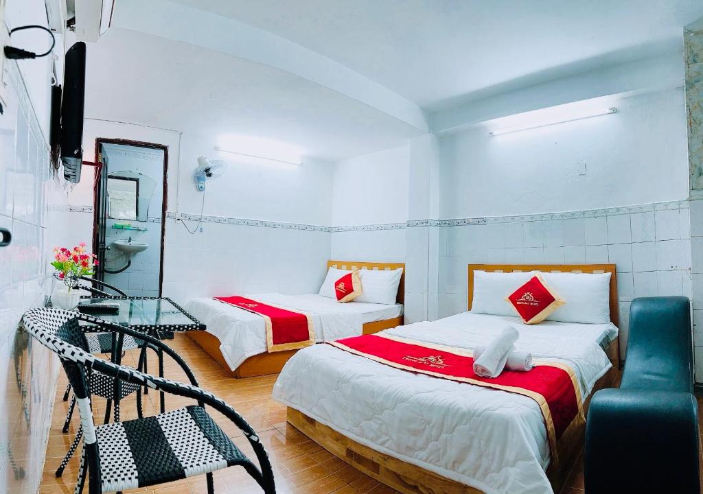 een slaapkamer met 2 bedden, een stoel en een spiegel bij Trung Bảo Hotel in Ho Chi Minh-stad