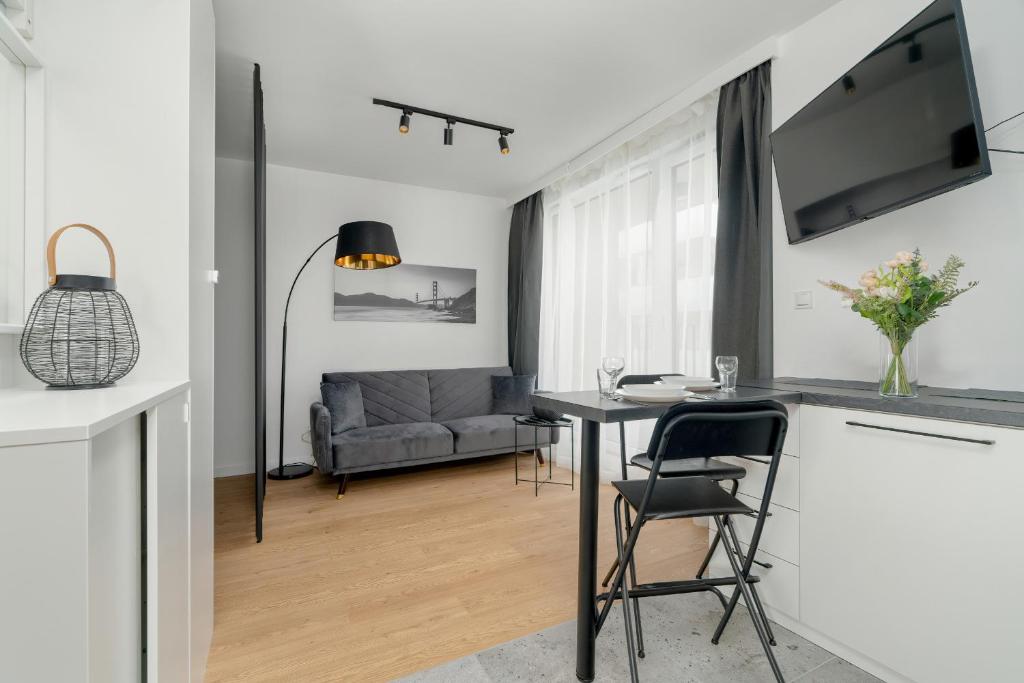 uma cozinha e sala de estar com uma mesa e um sofá em Apartment Szamarzewskiego with Balcony Poznań by Renters em Poznań