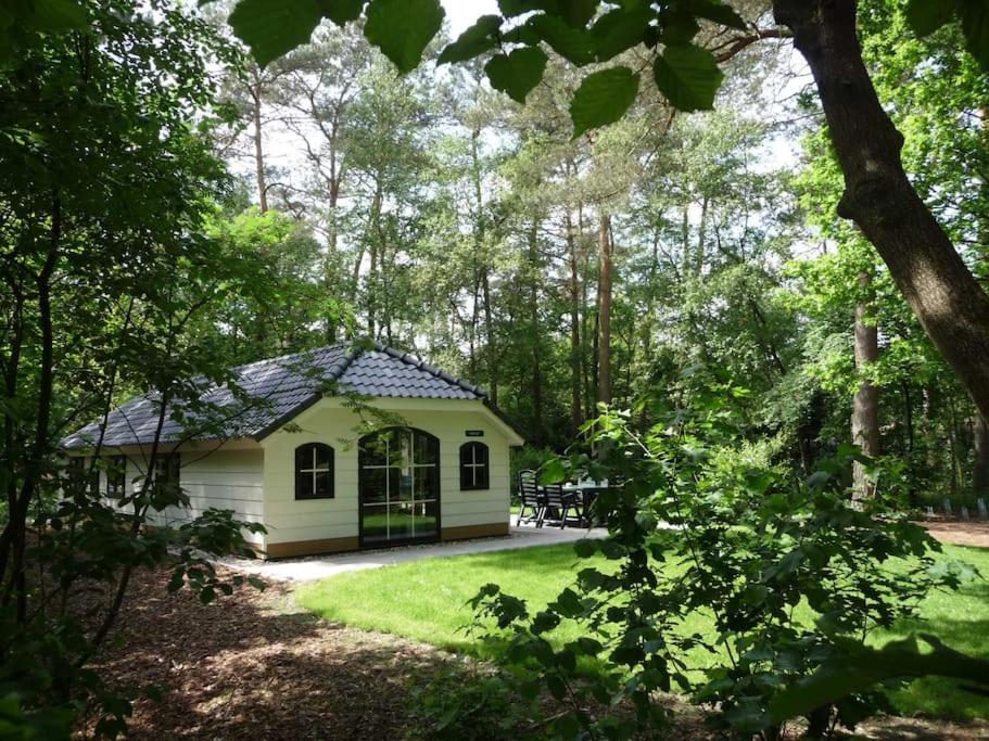 a small white cabin in the middle of a forest at Korhoen - 6p HeideBungalow met bedstee in Otterlo