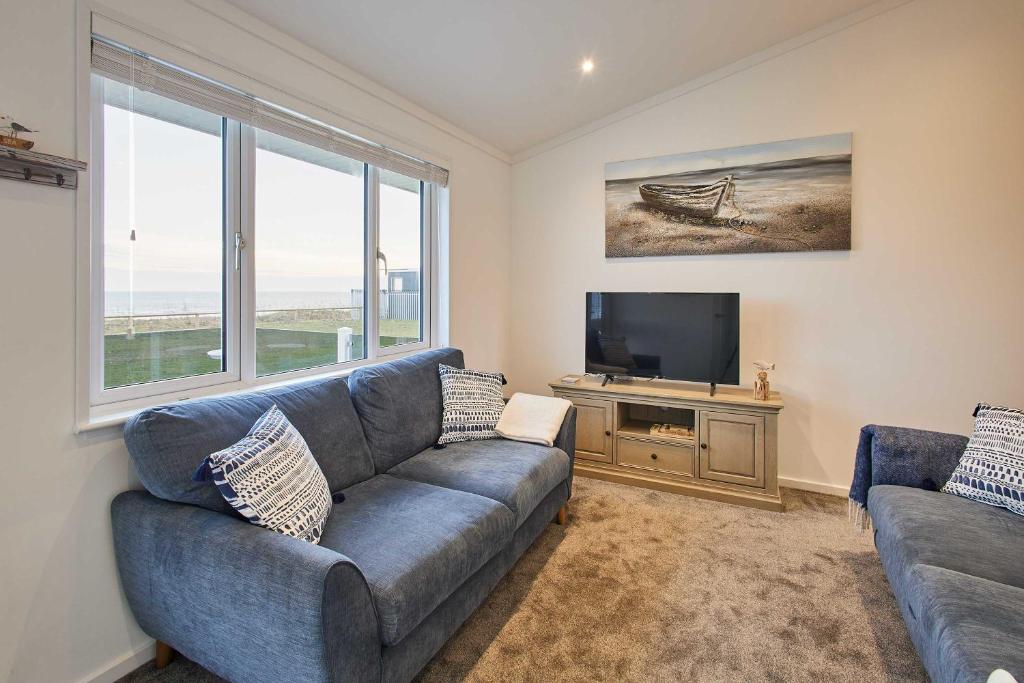 a living room with a blue couch and a flat screen tv at Host & Stay - Sea View Road in Bessingby