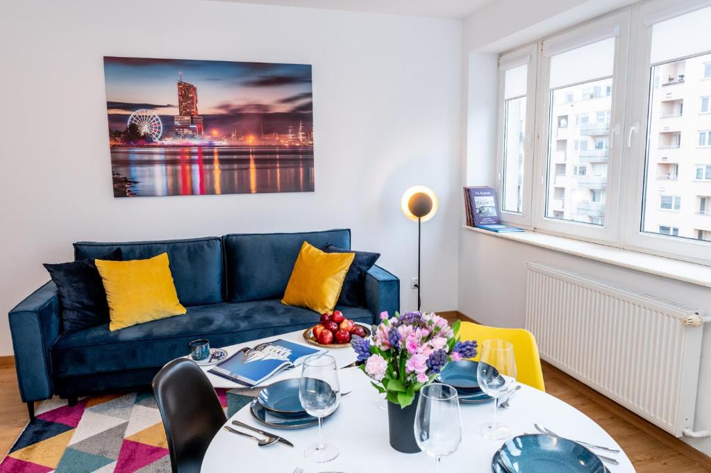 een woonkamer met een blauwe bank en een tafel bij Apartament w Redłowie - Legionów in Gdynia