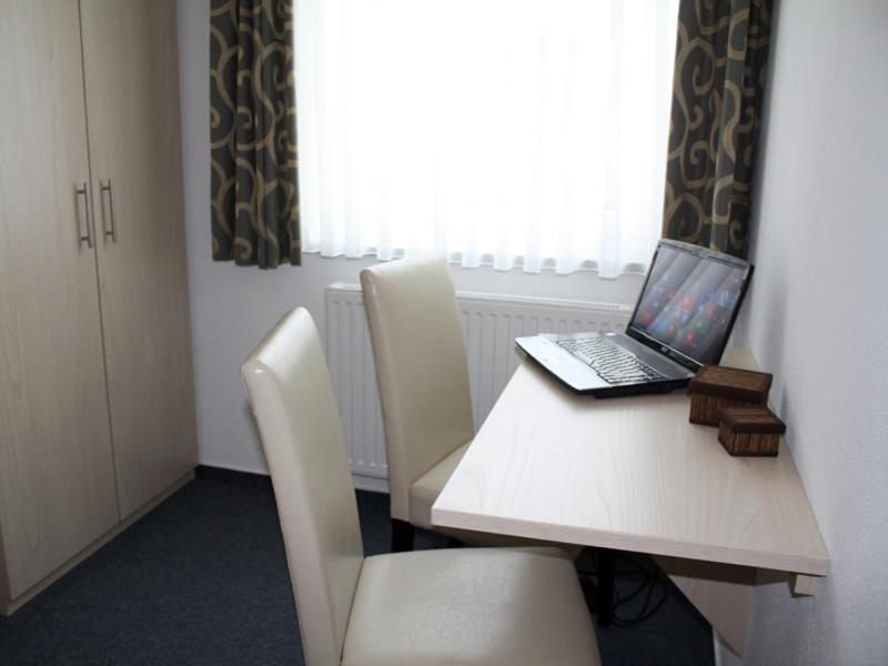 een laptop op een tafel met stoelen bij Pension Stadler in Obertraubling