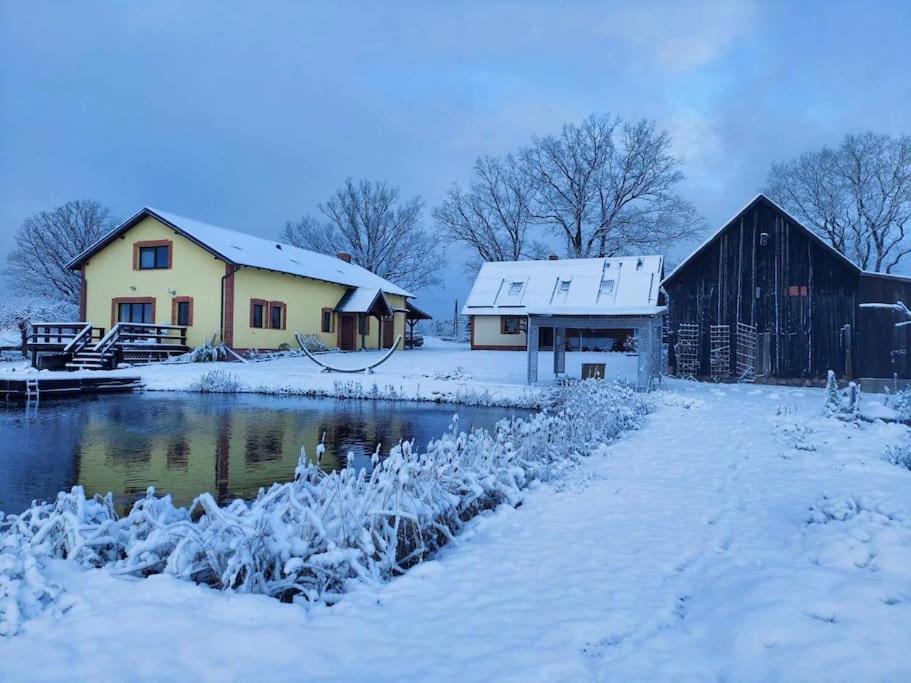 une maison et une grange dans la neige dans l'établissement Pod Dębem, à Bartel Wielki