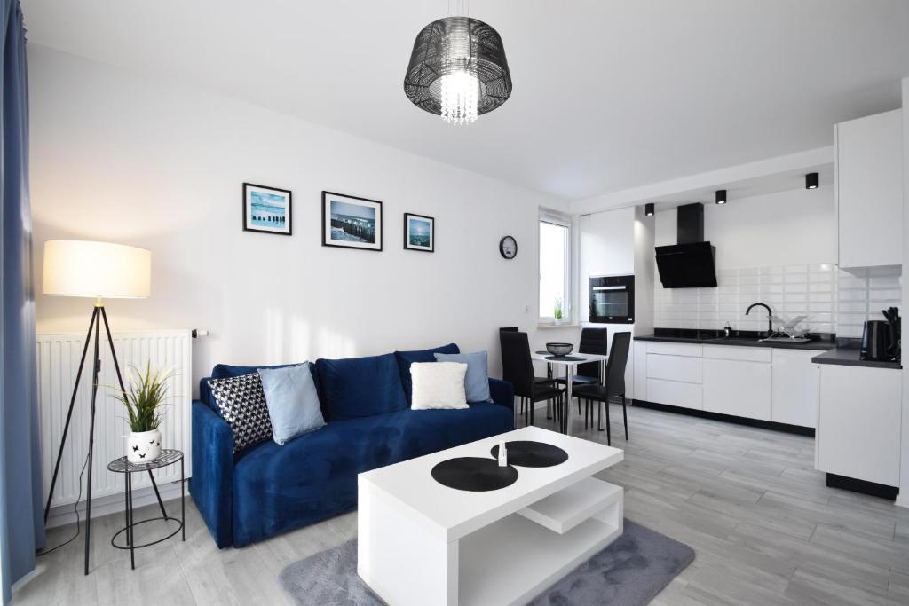 a living room with a blue couch and a kitchen at RentPlanet - Apartament Biały Dom in Kołobrzeg