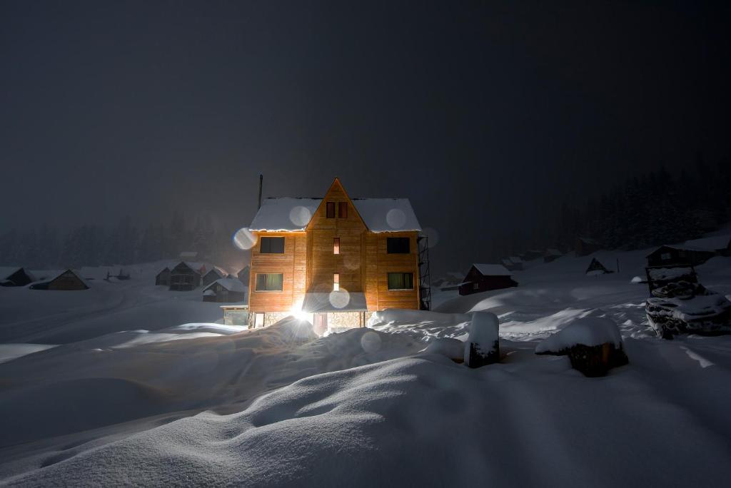 une maison éclairée la nuit dans la neige dans l'établissement Bakhmaro Continent, à Chʼkhakoura