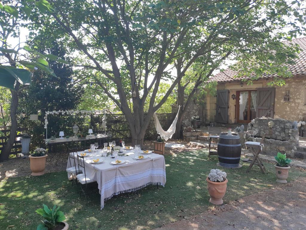 una mesa con un mantel blanco bajo un árbol en Chez Géraldine, en Montels