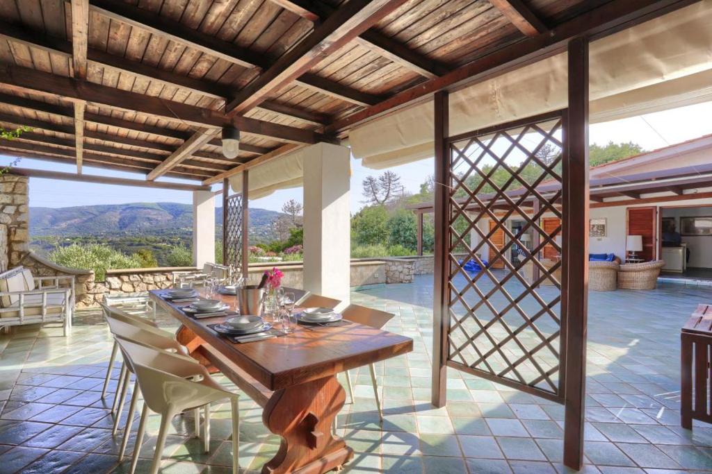 an outdoor dining room with a wooden table and chairs at Residence Les Oliviers in Porto Azzurro