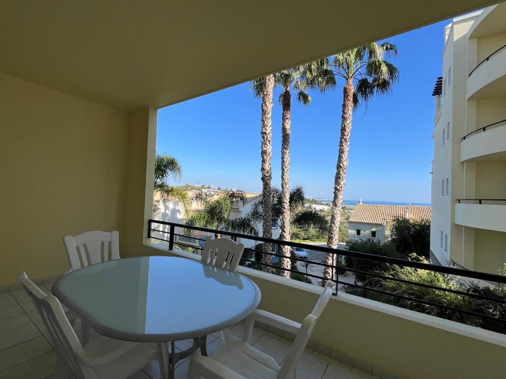 a table and chairs on a balcony with palm trees at Apart com vista mar a 2min praia in Lagos