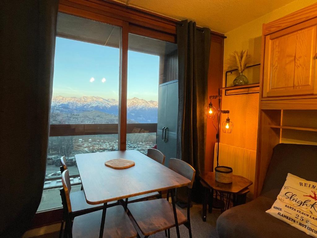un salon avec une table et une grande fenêtre dans l'établissement Studio tout confort pied des pistes avec balcon et wifi, à Villarembert