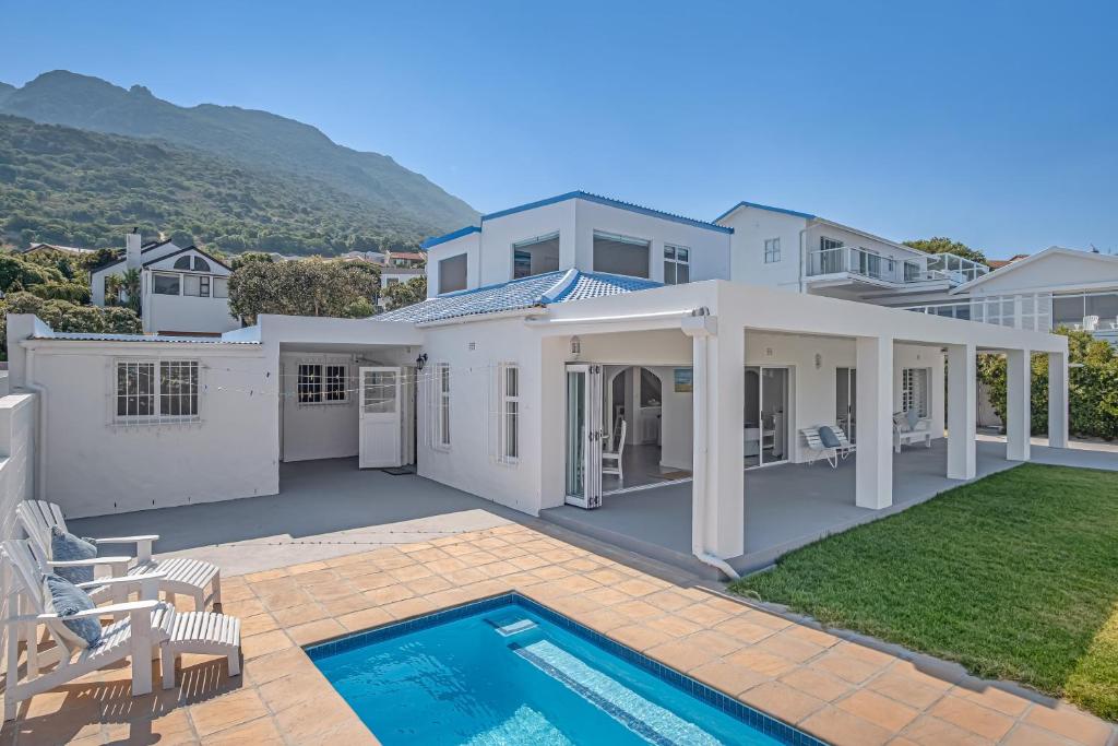 a large white house with a swimming pool at Cockleshells Beach Cottage in Cape Town