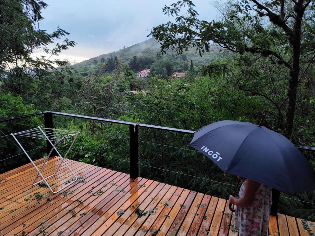 a person with an umbrella standing on a deck at Cedro Azul in La Cumbre