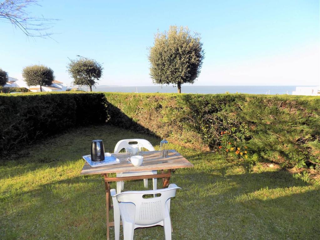 une table et deux chaises assises dans l'herbe dans l'établissement Royan - Plage du Chay - APPARTEMENT en REZ-DE-JARDIN avec APERCU MER, à Royan