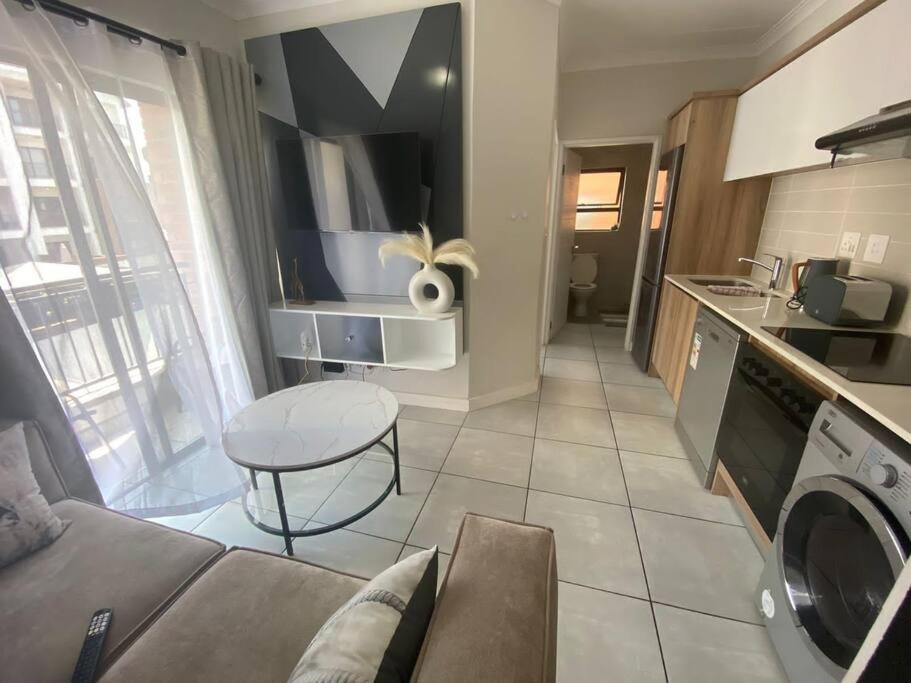 a kitchen and living room with a couch and a table at One Bedroom The Blyde in Pretoria