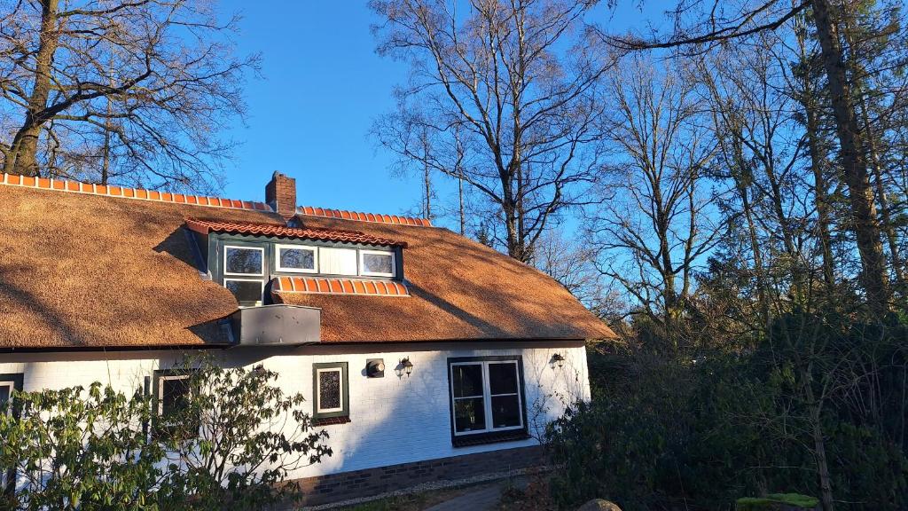 uma casa branca com telhado castanho e árvores em Familiehuis De Erica - 12 p em Otterlo