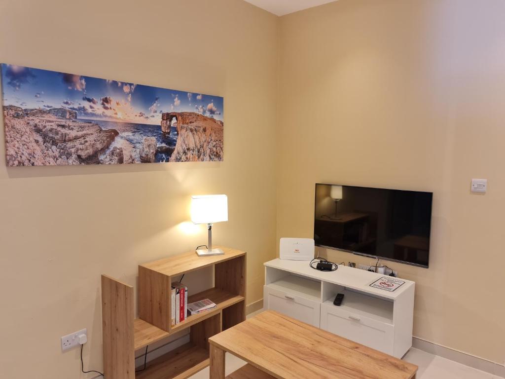 uma sala de estar com televisão e uma mesa com candeeiro em Tarxien - Lovely 3 bedroom unit em Tarxien