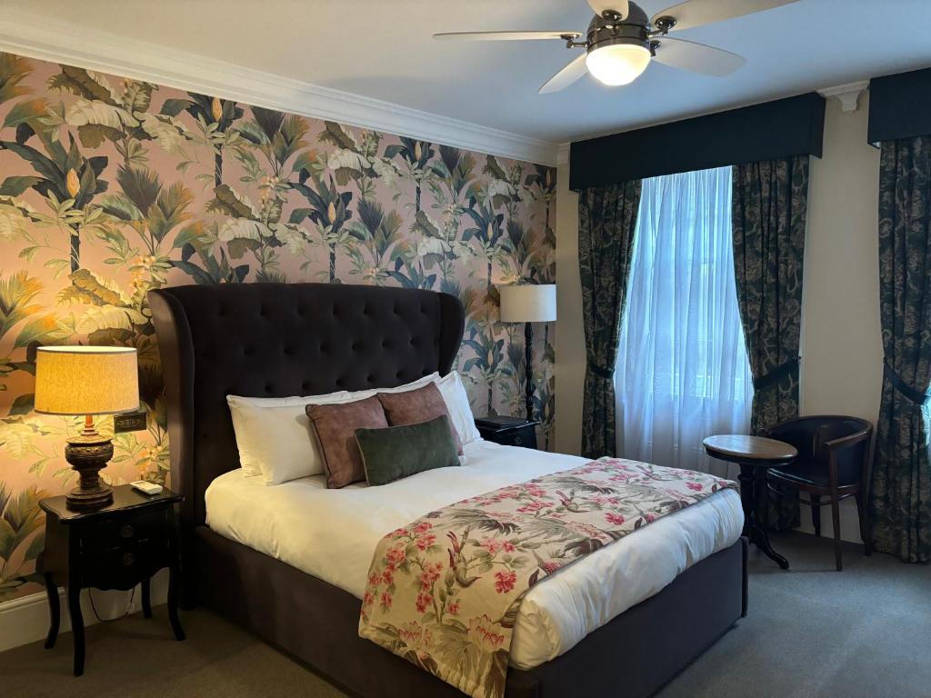 1 dormitorio con 1 cama y papel pintado con motivos florales en The Clerk & Well Pub and Rooms en Londres