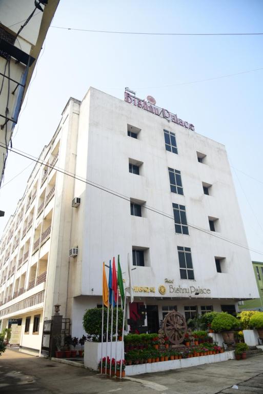 een groot wit gebouw met vlaggen ervoor bij Hotel Bishnu Palace in Jhārsuguda