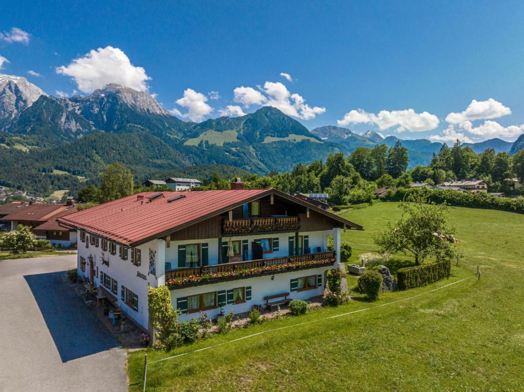 una casa con techo rojo con montañas al fondo en Gästehaus Bodnerlehen en Schönau am Königssee