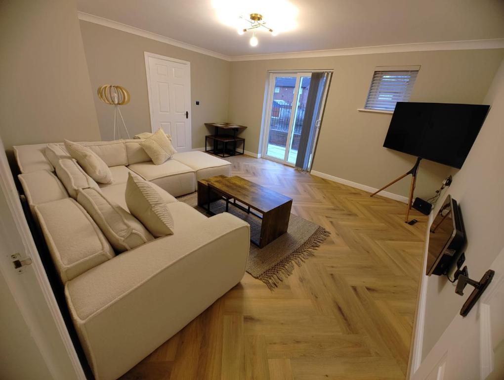 a living room with a white couch and a table at New 2 Bedroom Appartment In Manchester - Stretford - Old Trafford Close to Football-Cricket Ground & City Centre in Manchester