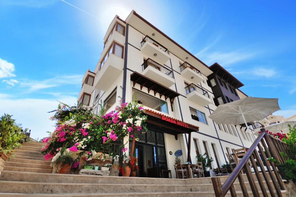 a building with flowers and an umbrella and stairs at Doada Hotel in Datca