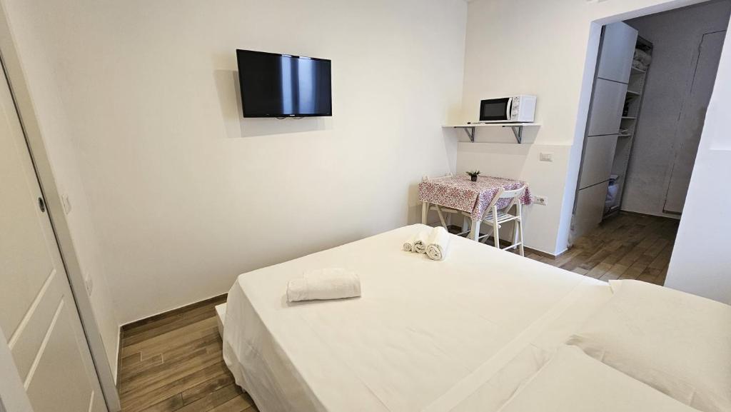 a white room with a bed and a tv on the wall at Casteddu Cagliari centro in Cagliari