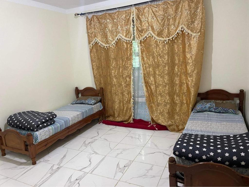 um quarto com duas camas e uma janela com cortinas em Très belle appartement em Constantina
