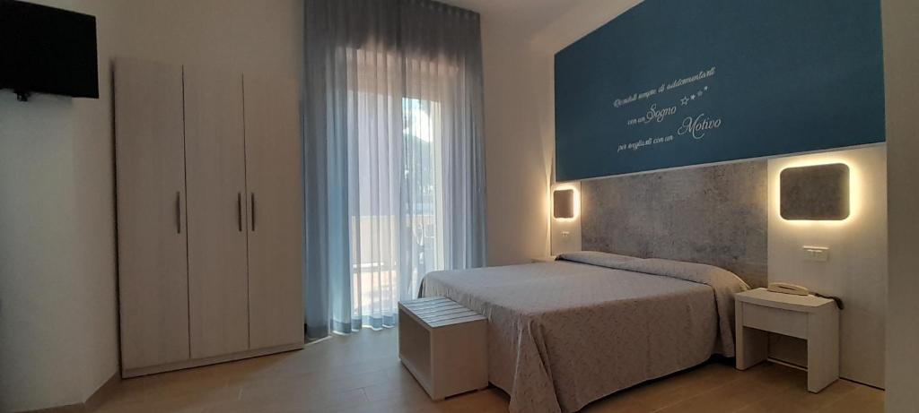 um quarto com uma cama e uma grande janela em I Monolocali Del Boccaccio em Milano Marittima