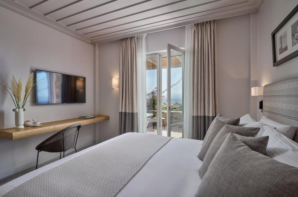 a bedroom with a bed and a desk and a window at Summer Senses Luxury Resort in Logaras