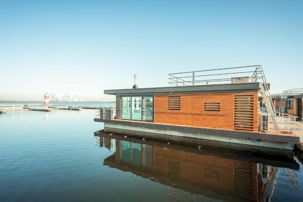 mały drewniany dom na przystani w wodzie w obiekcie Hausboot Dicke Bärta w mieście Klitten