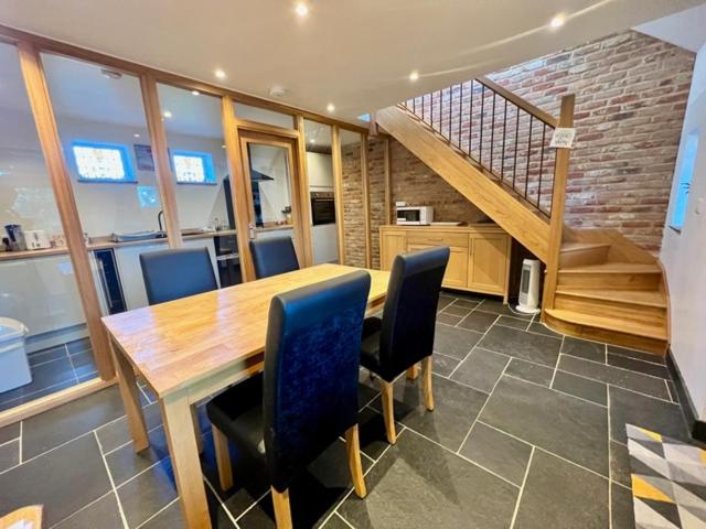 a dining room with a table and chairs and a staircase at New Bury Cottage near Goodwood in Chichester