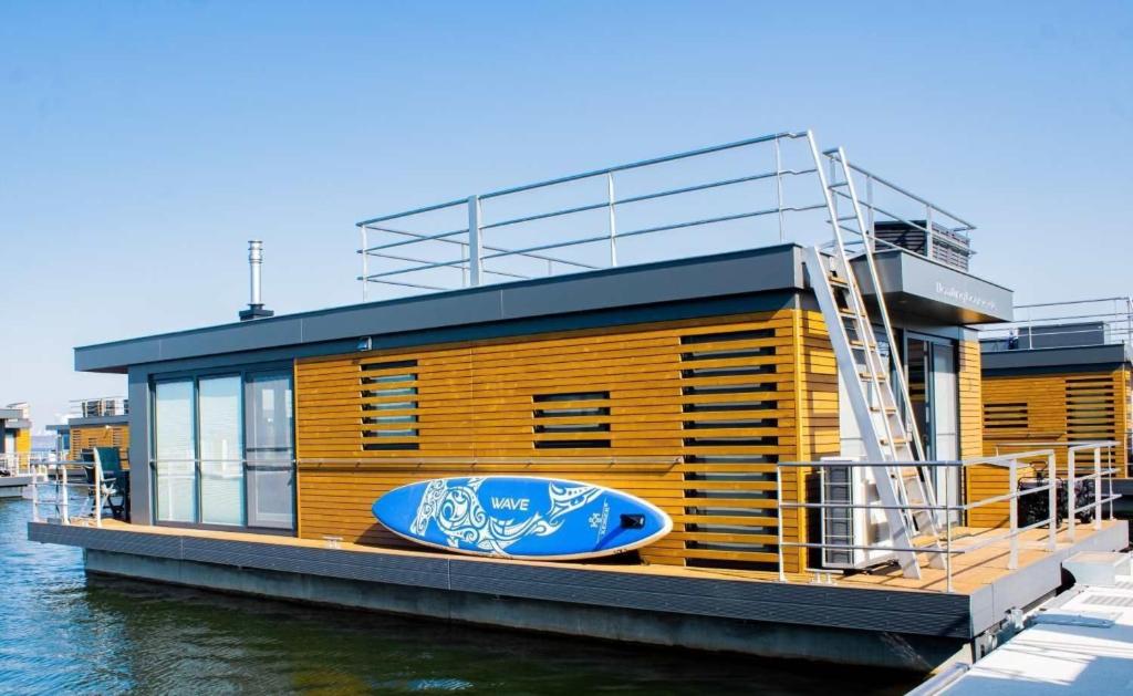 un bâtiment sur l'eau avec une planche de surf sur lui dans l'établissement Hausboot Schatzinsel, à Klitten