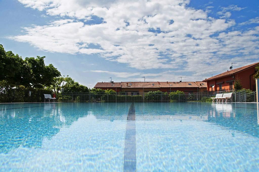 a large blue swimming pool with a building in the background at Da Chiara in Lazise