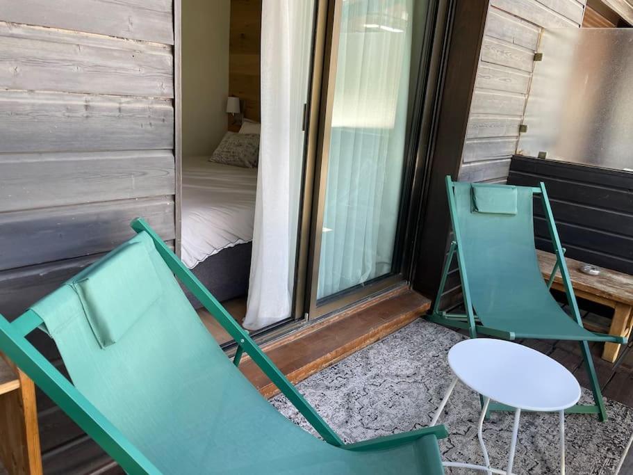 two green chairs sitting on a porch with a bed at Family cocoon Prime Rochebrune location in Megève
